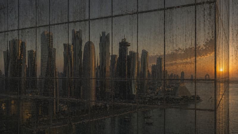 Dirty window with dust, streaks, and water spots obscuring the Doha skyline — before SKYNA cleaning